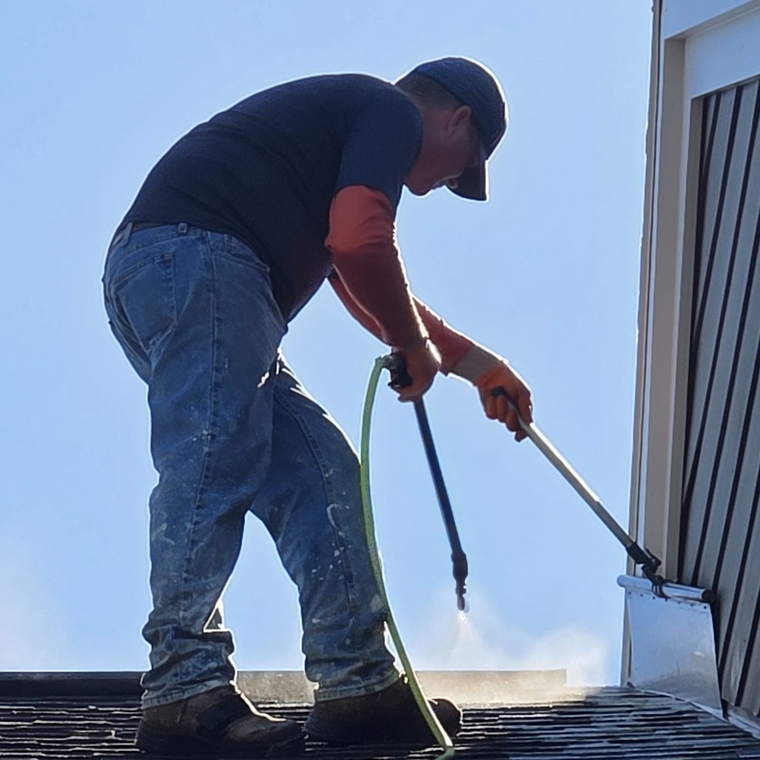 Applicator spraying SoyFuze soy oil roof rejuvenation treatment with the professional spray wand and spray shield