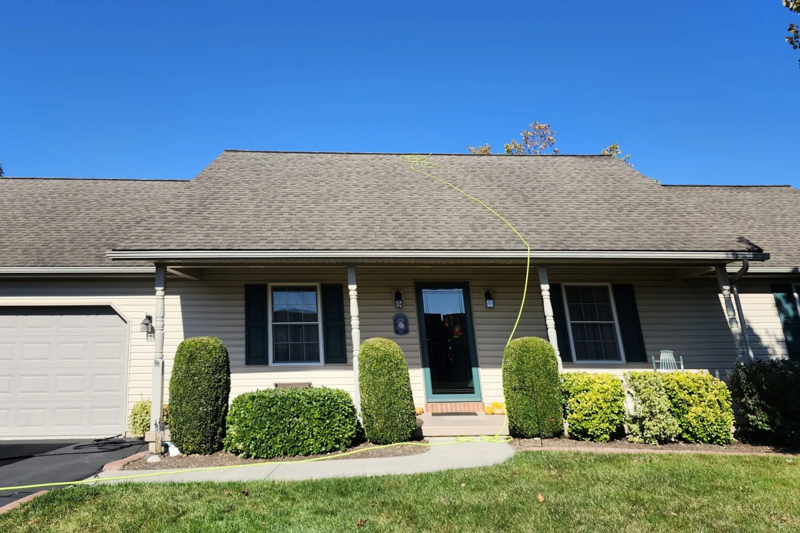 Weathered gray asphalt shingle roof on a single-story house with a front porch before soy oil roof treatment